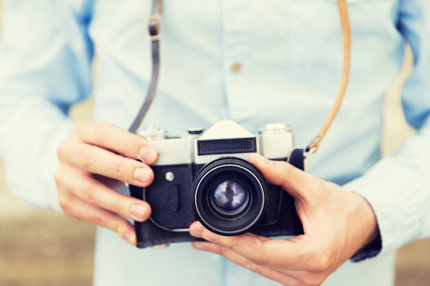 persone, fotografia, tecnologia, tempo libero e stile di vita - primo piano di un giovane hipster con una cinepresa vintage retrò sulla strada della città