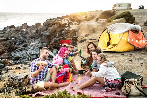 Persone hipster che prendono selfie alla festa in campeggio in spiaggia