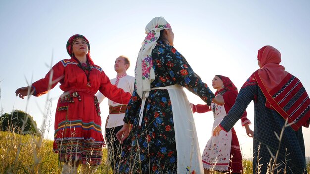 Persone in abiti tradizionali russi che eseguono una danza rotonda sul campo