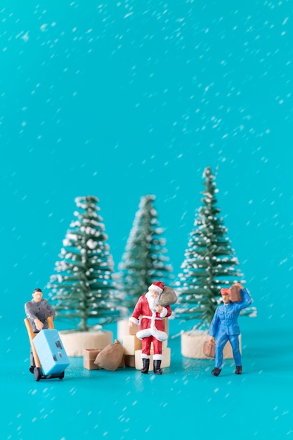 Persone in miniatura Babbo Natale e il suo team di lavoratori stanno preparando regali