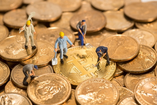 persone in miniatura che lavorano su Bitcoin dorato di criptovaluta e denaro contante in dollari