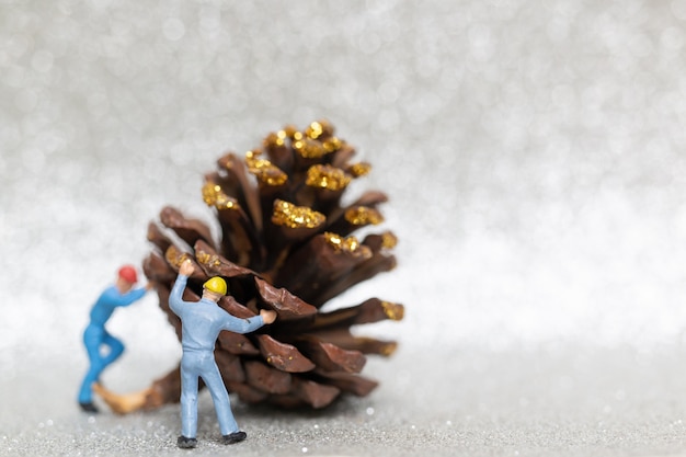 Persone in miniatura con la squadra di lavoratori che prepara una pigna di Natale