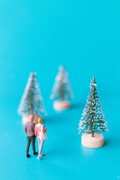 Persone in miniatura, coppia innamorata in piedi accanto a un albero di Natale, concetto di Natale e felice anno nuovo.