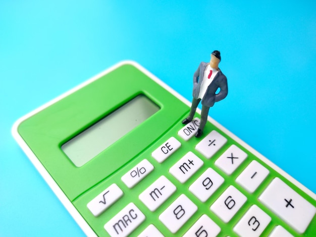 Persone in miniatura e calcolatrice su sfondo blu Idea del concetto di business