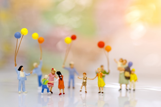 Persone in miniatura, famiglia e bambini con palloncini colorati, concetto di famiglia.