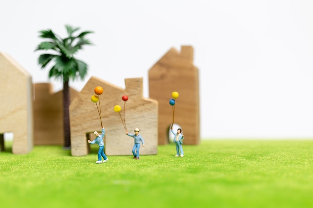 Persone in miniatura: famiglia felice che cammina in campo con palloncini