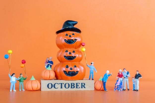 Persone in miniatura Famiglia felice con zucca su sfondo arancione, Ciao ottobre concept