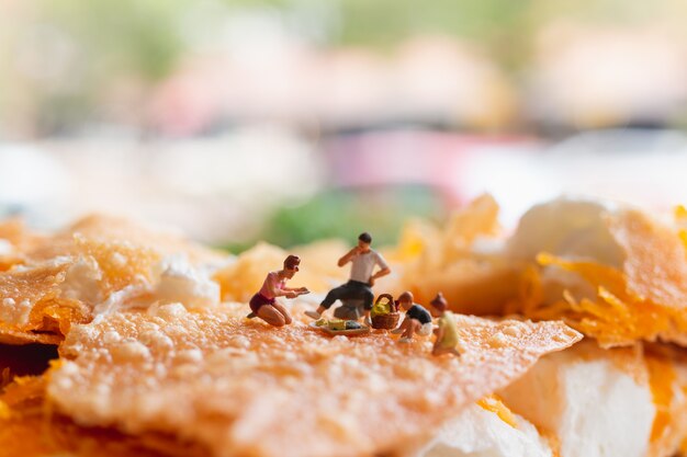 Persone in miniatura: famiglia felice seduto sul tappeto durante un picnic sul dessert