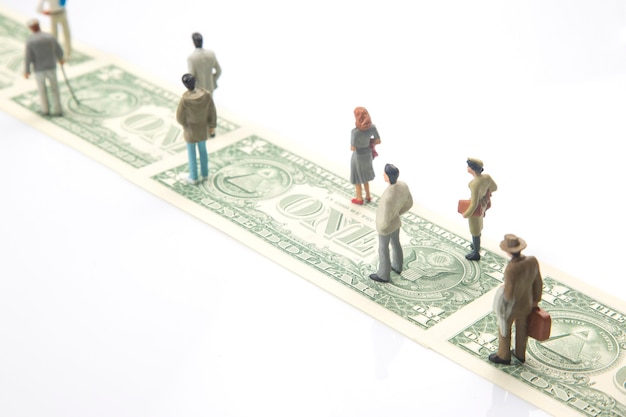 Persone in miniatura. figurine di persone percorrono la strada dai soldi in dollari al loro successo nella vita. concetto di indipendenza finanziaria