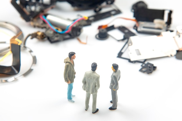 Persone in miniatura Gli uomini d'affari si trovano vicino a parti smontate di un dispositivo elettronico Concetto di imprenditore aziendale