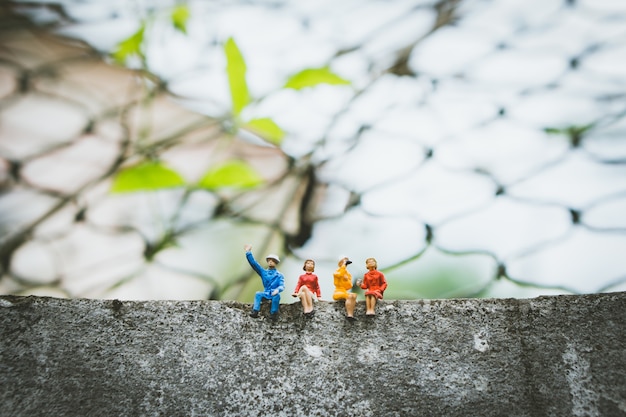 Persone in miniatura - gruppo di persone sedute sul muro