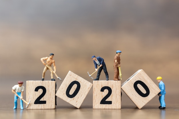 Persone in miniatura: il gruppo di lavoratori crea il blocco di legno numero 2020