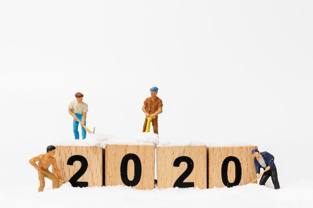 Persone in miniatura, il gruppo di lavoro crea il blocco di legno numero 2020