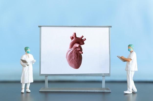 Persone in miniatura Il medico sta diagnosticando malattie cardiache sullo schermo