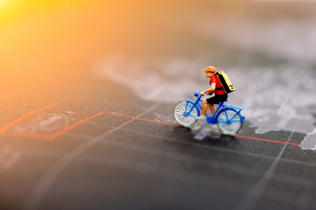 Persone in miniatura in bicicletta sulla mappa del mondo. Concetto di viaggio, sport e affari.