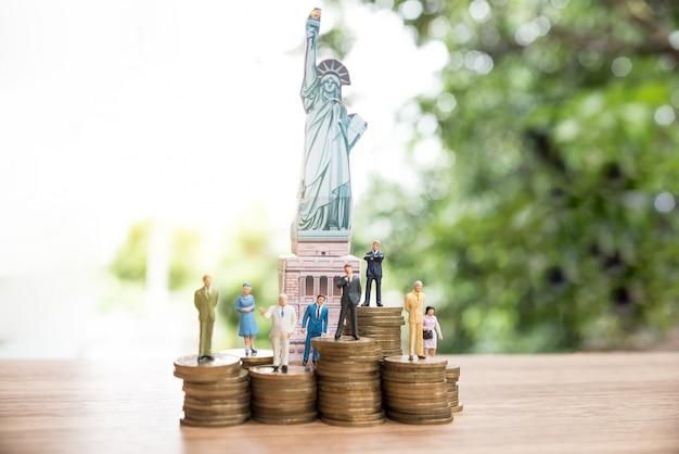 Persone in miniatura in piedi sulla moneta con la statua della libertà