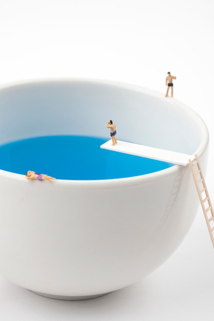 Persone in miniatura nella tazza tazza piscina