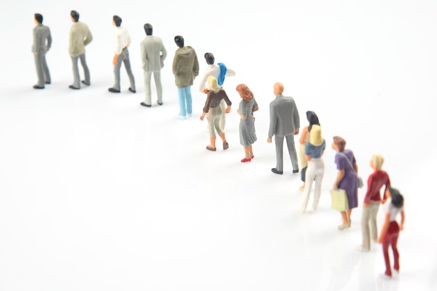 Persone in miniatura. persone diverse stanno in fila una dopo l'altra su uno sfondo bianco. comunicazione della società di diverse generazioni