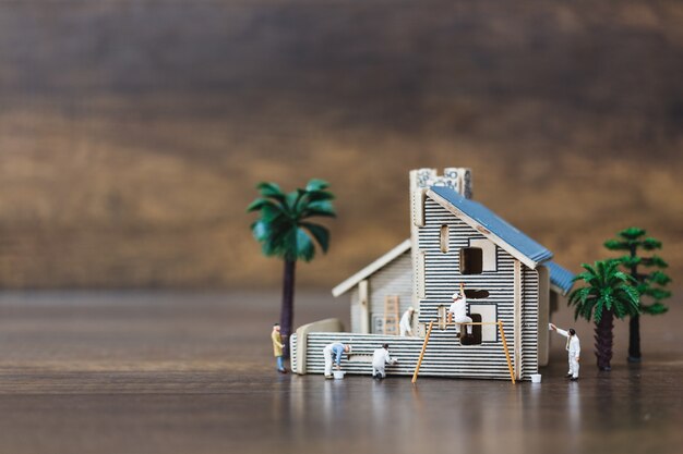 Persone in miniatura: squadra di lavoratori che dipinge una nuova casa.