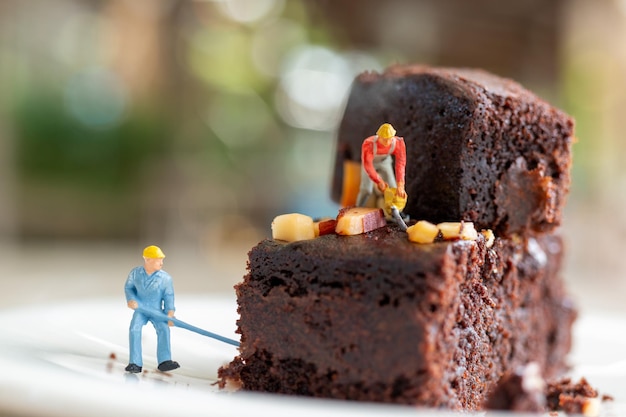 Persone in miniatura Un impiegato sta preparando un biscotto al cioccolato