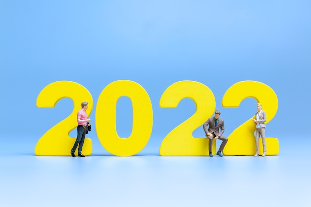 Persone in miniatura: uomini d'affari in piedi sul numero 2022, concetto di felice anno nuovo