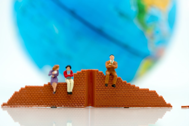 Persone in miniatura: uomo d'affari in piedi con muro e mondo. Concetti di problem solving.