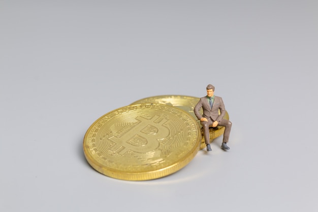 Persone in miniatura Uomo d'affari seduto su monete Bitcoin