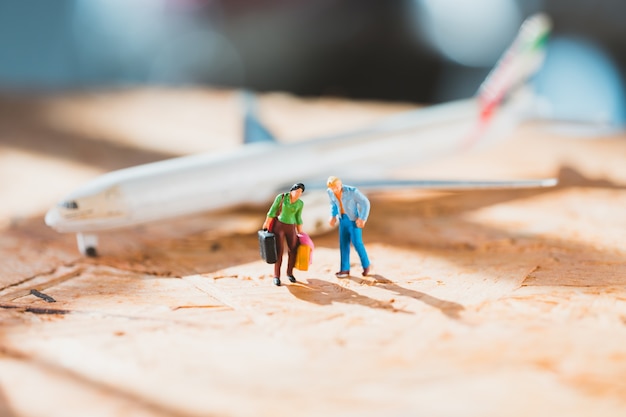 Persone in miniatura, uomo e donna che camminano su sfondo aereo utilizzando come viaggio e concetto di famiglia