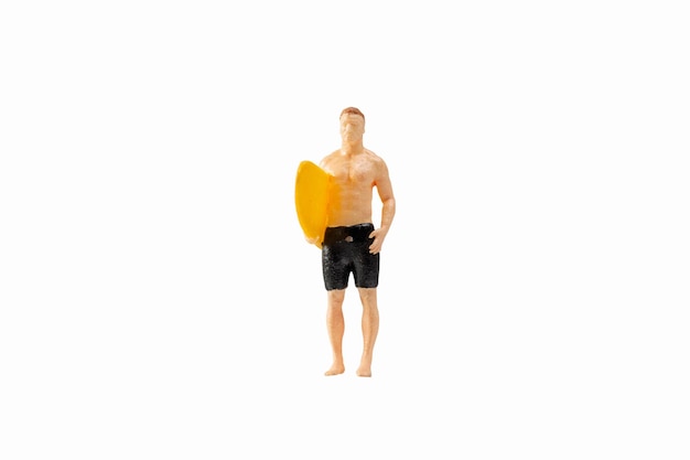 Persone in miniatura uomo in costume da bagno e in possesso di una tavola da surf gialla isolata su sfondo bianco con tracciato di ritaglio