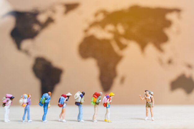 Persone in miniatura viaggiatori che camminano sulla mappa del mondo