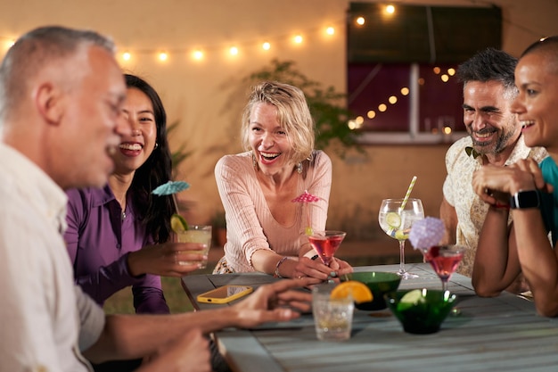Persone mature di mezza età che bevono cocktail, festeggiano insieme, un gruppo di amici che applaudono, bevono bicchieri.