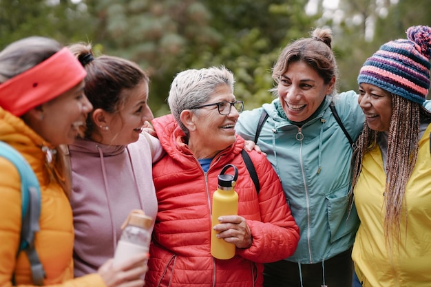 Persone multirazziali che si abbracciano all'aperto durante la giornata di trekking - Donne multigenerazionali che si divertono a fare escursioni nella natura