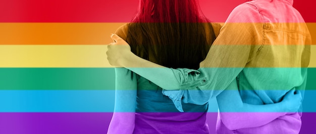 persone, omosessualità, matrimonio omosessuale, gay e concetto di amore - primo piano di una coppia lesbica felice che si abbraccia sullo sfondo delle strisce della bandiera arcobaleno
