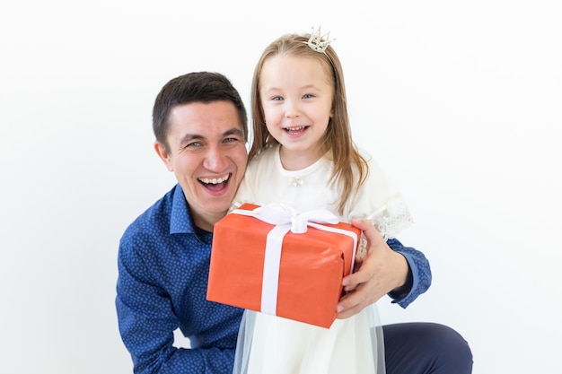 persone, paternità e concetto di famiglia - papà felice che tiene una confezione regalo con sua figlia su bianco