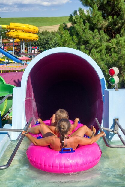 Persone pronte a scivolare sul gonfiabile rosa nello scivolo d'acqua nell'aquapark