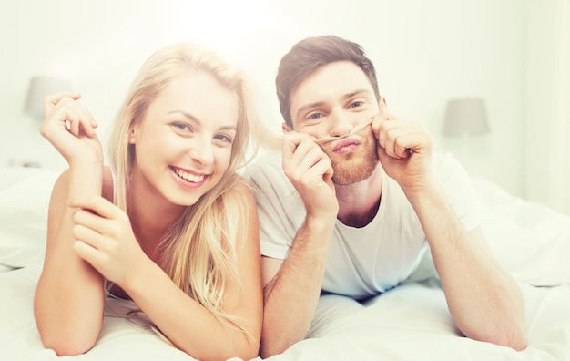 persone, riposo, amore, relazioni e concetto di felicità - coppia felice sdraiata a letto a casa