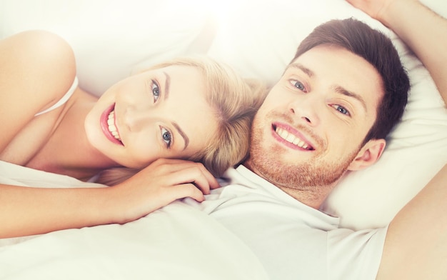 persone, riposo, amore, relazioni e concetto di felicità - coppia sorridente felice sdraiata a letto a casa