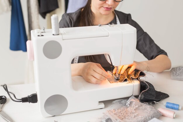 Persone, sarto e concetto di moda - Ritratto ad angolo alto di stilista sorridente con gli occhiali seduto a un tavolo.