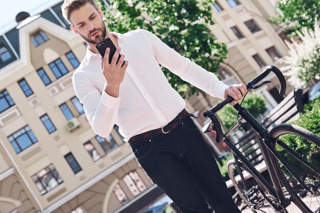 Persone tecnologia di comunicazione tempo libero e stile di vita hipster uomo con smartphone su bici a scatto fisso