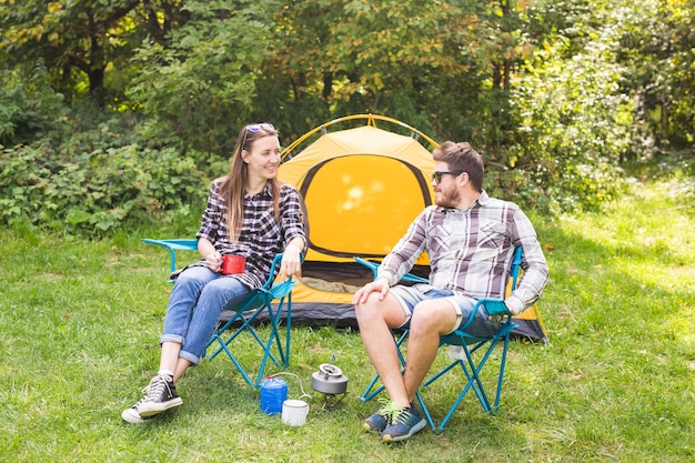 Persone, turismo estivo e concetto di natura - giovane coppia seduta vicino a una tenda.