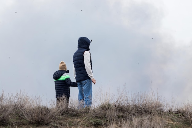 Persone uomo e bambino testimoni del fuoco in natura, persone sulla collina sullo sfondo di un'atmosfera fumosa
