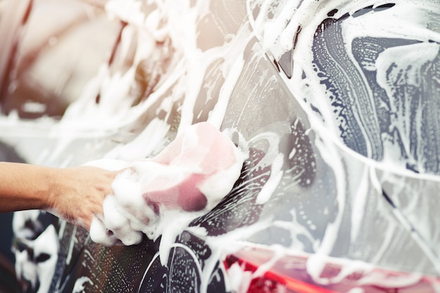 Persone uomo tenendo la mano rosa spugna per il lavaggio dell'auto. pulizia del pneumatico della ruota. Autolavaggio di concetto pulito.