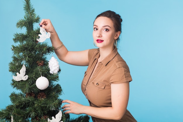 Persone, vacanze e concetto di natale - donna che decora l'albero di Natale sullo spazio blu