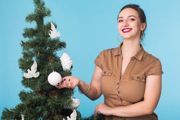 Persone, vacanze e concetto di natale - donna che decora l'albero di Natale sullo spazio blu