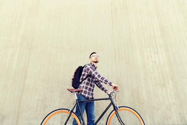 persone, viaggi, turismo, tempo libero e stile di vita - felice giovane hipster con bici a scatto fisso e zaino sulla strada della città