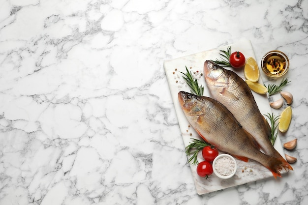 Pertiche e ingredienti crudi freschi su un tavolo di marmo bianco piatto con spazio per il testo Pesce di fiume