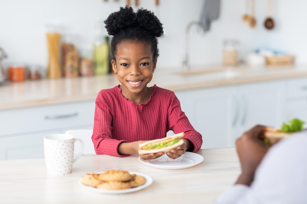 Pertty bambina nera che mostra il suo gustoso panino