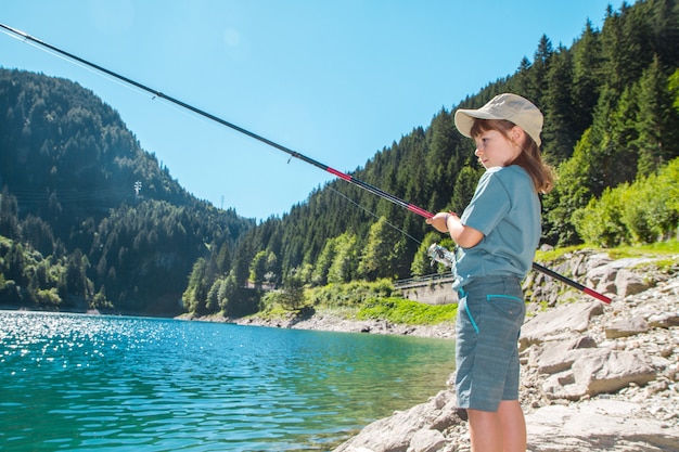 Pesca della ragazza in uno stagno nelle montagne