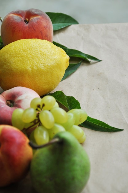 Pesca fresca e nettarina con foglie verdi limone e pera su carta artigianale Vista dall'alto Copia spazio