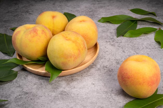 Pesca gialla dorata in piatto di legno su fondo grigio